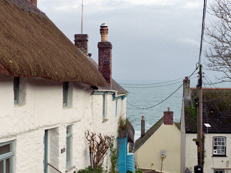 Whitewashed thatched cottage on a lane running down to the sea in Port Isaac, Cornwall