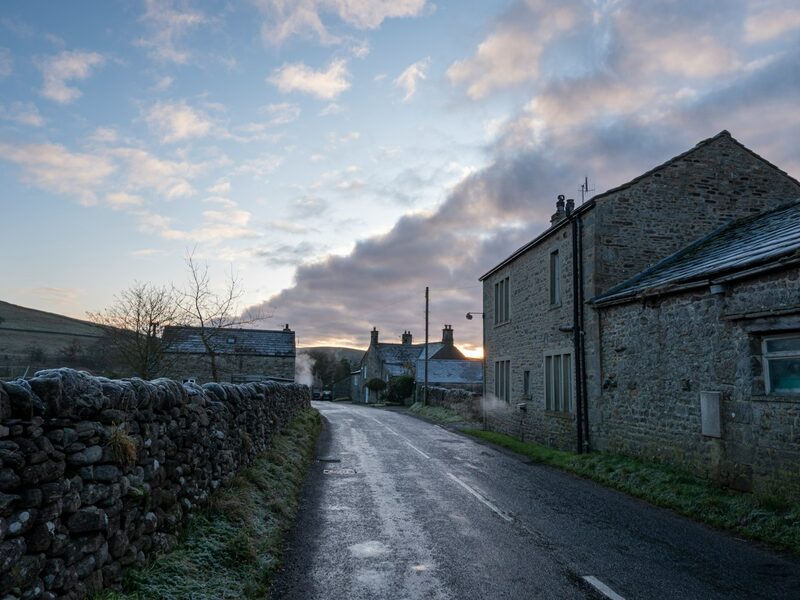 Stone Dales farmhouse beside a wet lane at dusk near Hawes, Yorkshire